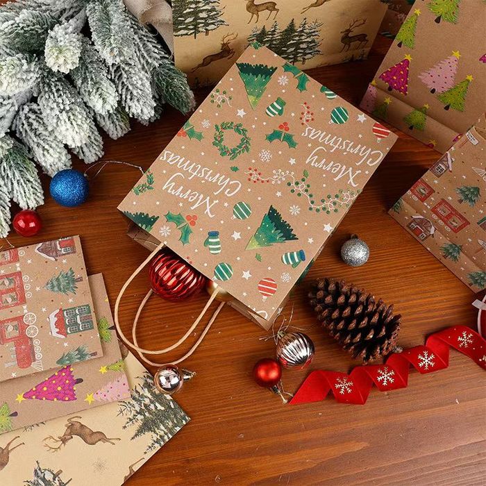 Flat lay of kraft Christmas wrapping paper sheets with a printed gift bag and pine cones
